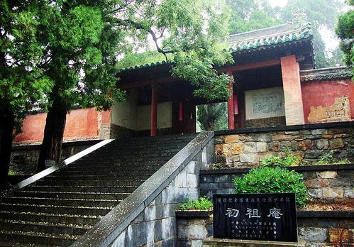 Ancient Chinese temple entrance with stone steps, trees, and traditional green-tiled roof