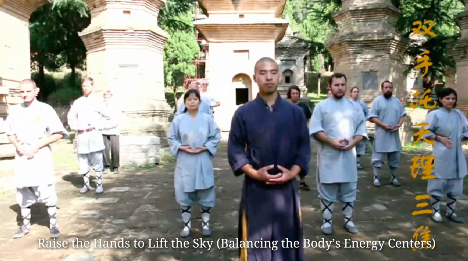 Group practicing Shaolin qigong meditation in temple courtyard with monks in traditional robes