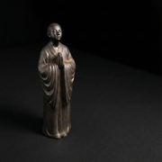 Buddhist monk statue with hands in prayer, serene expression, dark finish, for altar or mindfulness decor