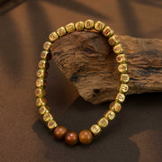 Golden prayer beads with engraved symbols, resting on rustic wood for mindful meditation.