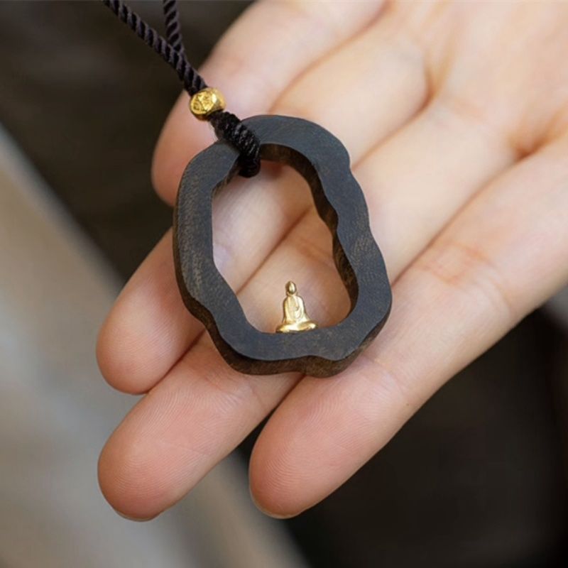 Wooden pendant with tiny gold Buddha, held in hand, for mindfulness and peace