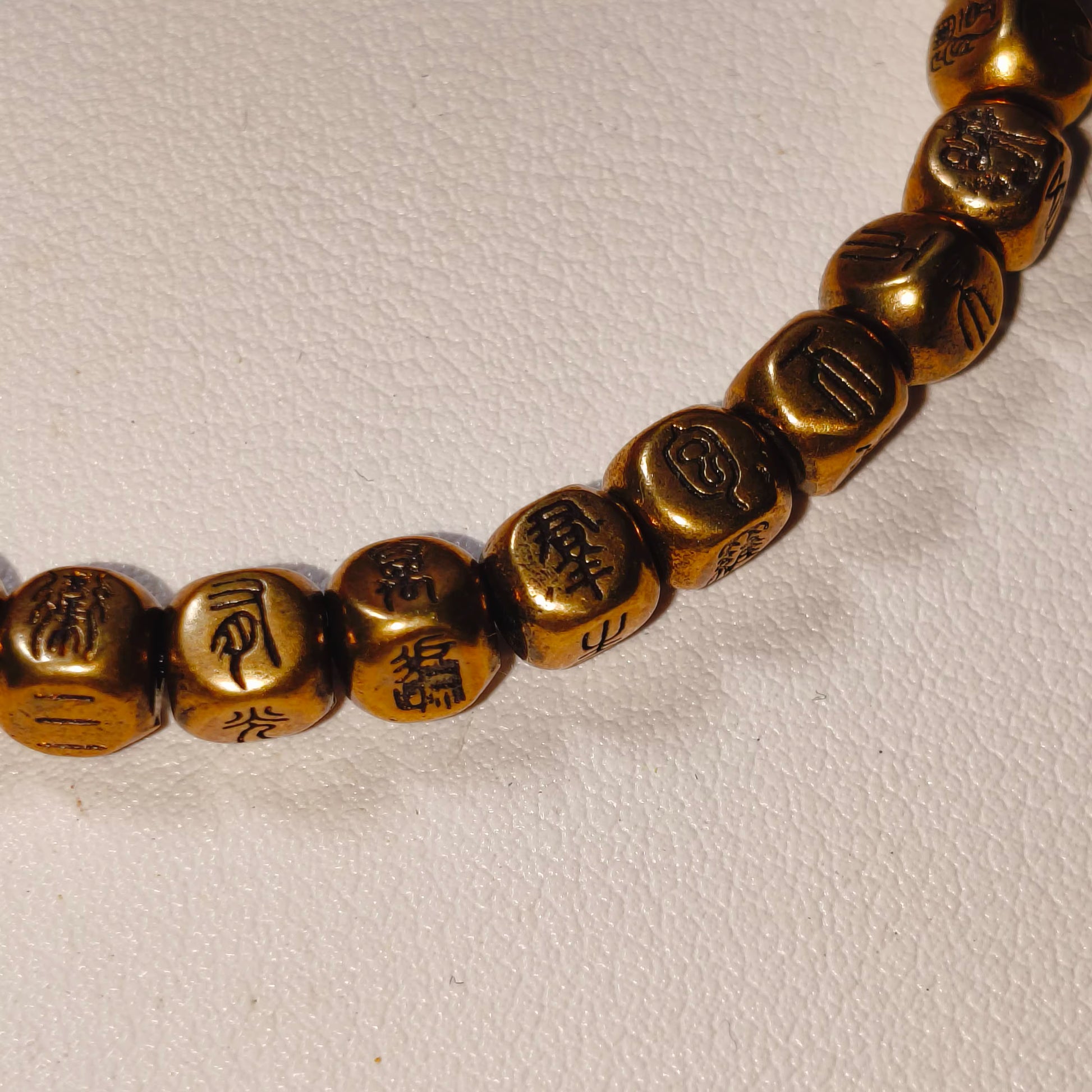 Golden Buddhist prayer beads with engraved sacred symbols, ideal for mindfulness and meditation practice.